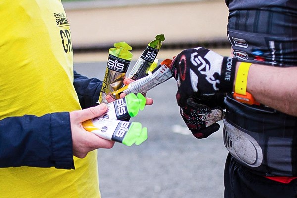 A steward showing a cyclist a range of SiS Energy gels on offer.